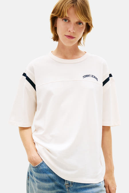 T-shirt blanc à manches courtes de TOMMY JEANS, avec des détails bleu marine sur les manches et un jean décontracté.