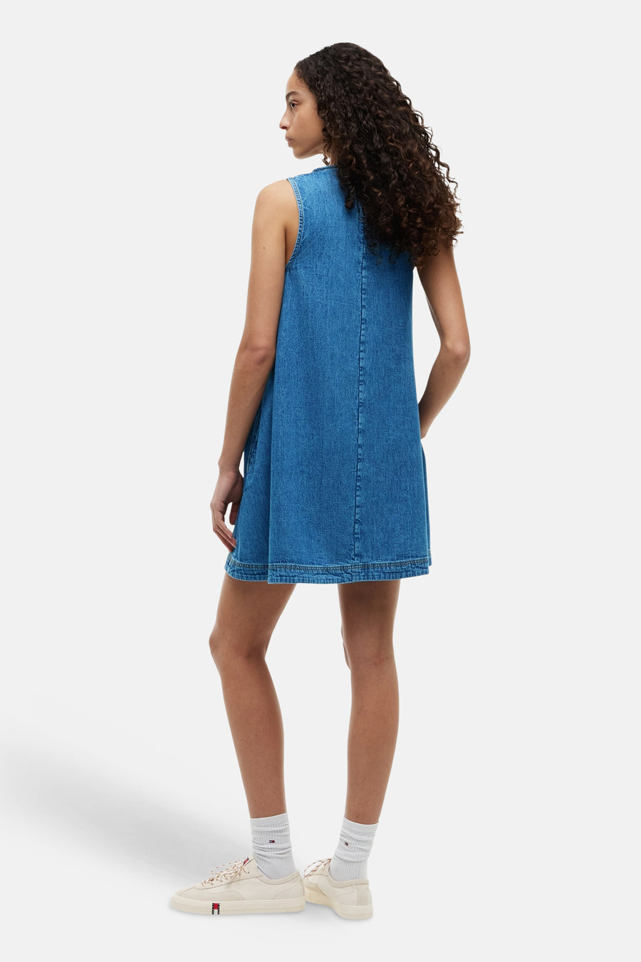 Robe en jean à manches courtes de TOMMY JEANS, avec une coupe droite et des baskets blanches avec chaussettes.