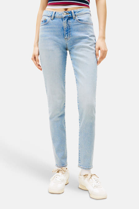 Jean slim bleu denim TOMMY JEANS, avec un étiquette de marque et un drapeau rouge-blanc-bleu sur la poche arrière.
