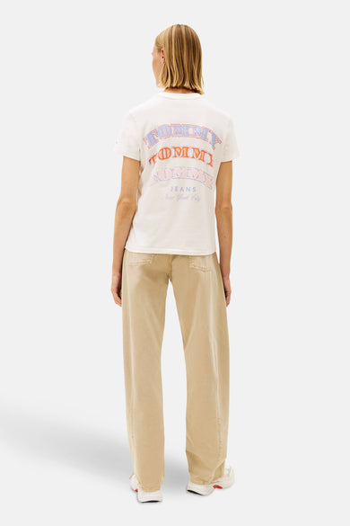 Ecru T-shirt met korte mouwen van TOMMY JEANS, met kleurrijke print op de rug, gecombineerd met beige broek en witte sneakers.
