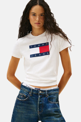 T-shirt blanc à manches courtes de TOMMY JEANS, avec logo sur la poitrine, associé à un gilet imprimé tigre et des shorts en denim.
