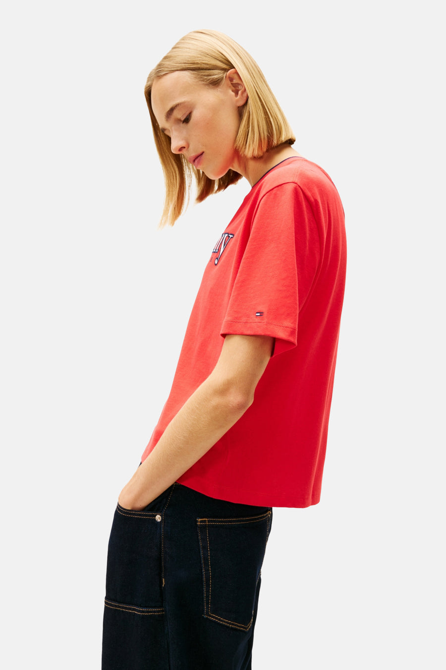 Vrouw in rood Tommy Hilfiger T-shirt en donkere jeans.
