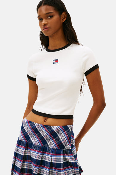 T-shirt blanc à manches courtes de TOMMY JEANS, avec des bordures noires, combiné à une jupe plissée à carreaux.