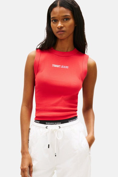 Haut rouge sans manches de Tommy Jeans, avec logo blanc sur la poitrine et assortie à un pantalon blanc.