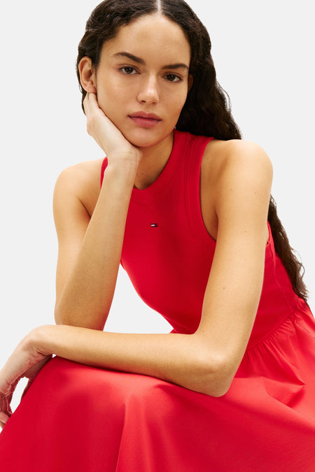 Robe rouge sans manches TOMMY JEANS, avec un logo minimaliste, sur une femme assise.