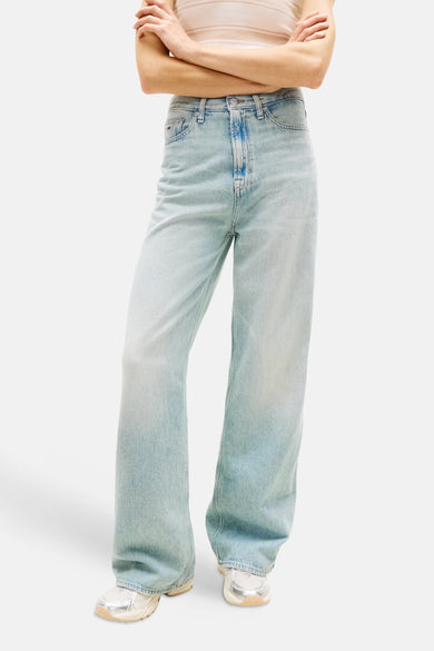 Jeans larges en denim bleu clair de Tommy Jeans, de couleur unie et à coupe ample, portées avec un polo rayé et des baskets.