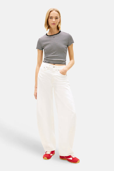 Off-white wijde jeans van TOMMY JEANS, gedragen met een gestreepte crop top en rode sneakers.