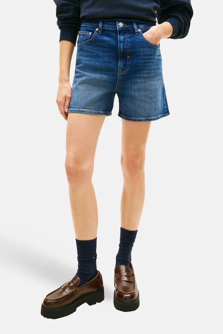 Short en jean bleu marine de TOMMY JEANS, porté avec un sweat-shirt bleu foncé à détails blancs et des mocassins marron avec chaussettes.