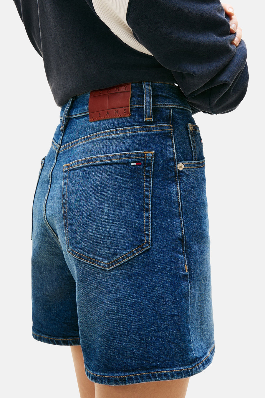 Short en jean denim bleu foncé de TOMMY JEANS, avec poches arrière et étiquette en cuir marron.