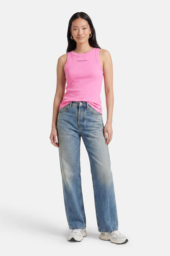 Roze ribbel tanktop van TOMMY JEANS met klein logo, gedragen met blauwe jeans en witte sneakers, front view