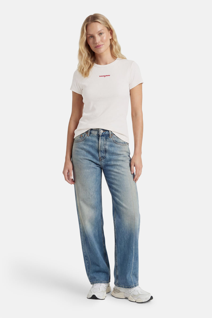 Witte korte mouwen T-shirt van TOMMY JEANS met rode logo op borst, gedragen met blauwe jeans en witte sneakers, front view