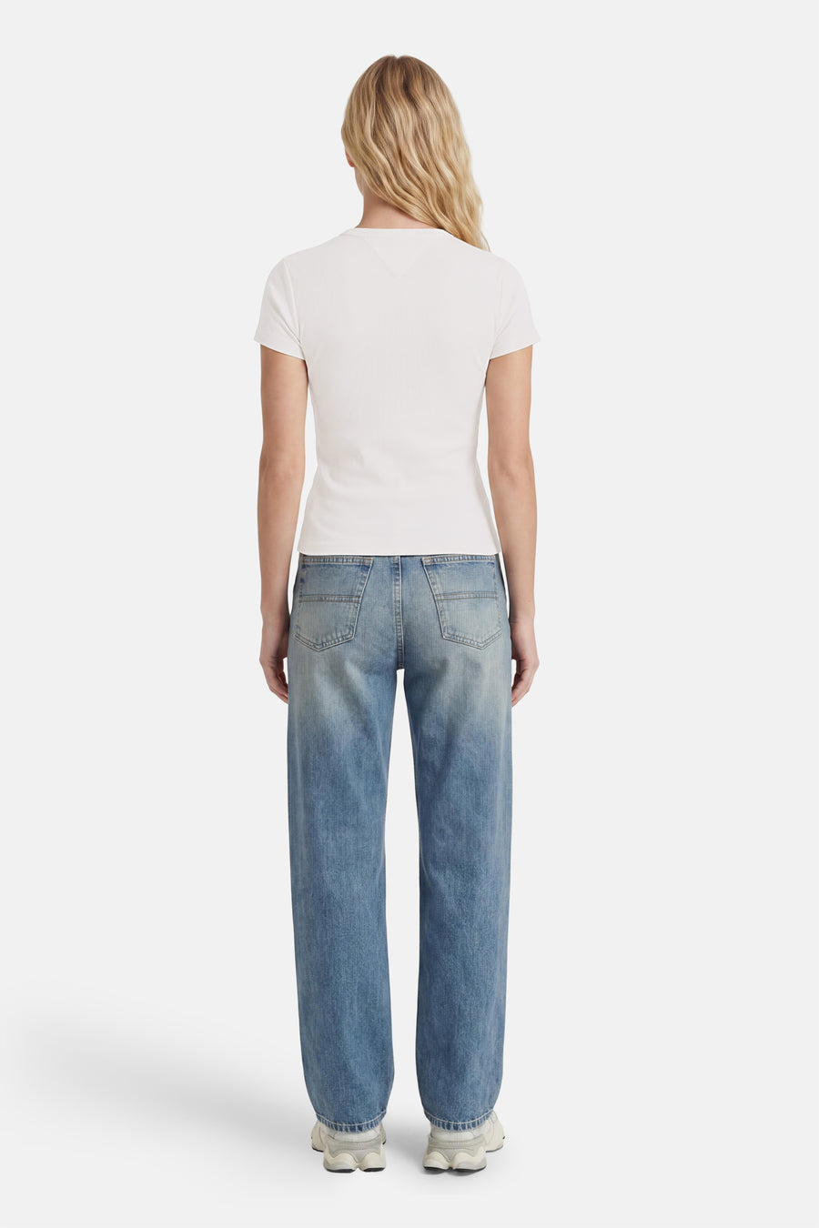 Witte korte mouwen t-shirt van TOMMY JEANS, strak model, achterkant weergegeven, gedragen met lichtblauwe jeans en witte sneakers