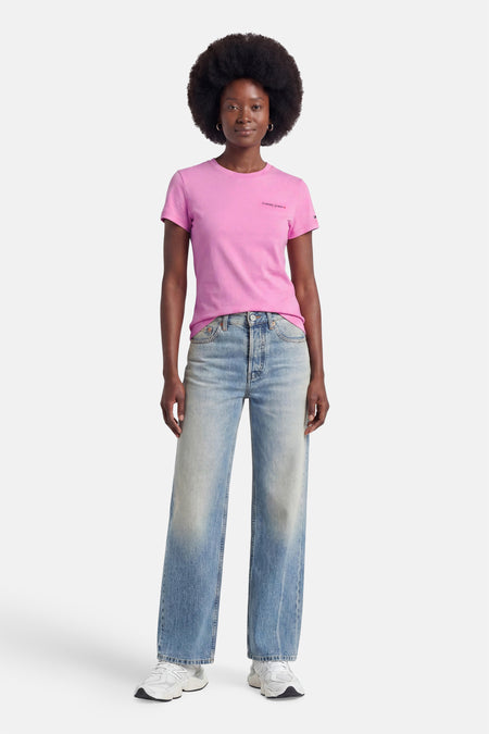 Roze korte mouwen T-shirt van TOMMY JEANS met klein logo op borst, gedragen met lichtblauwe jeans en witte sneakers, front view