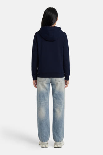 Donkerblauwe sweater met kap van TOMMY JEANS, achterzijde, gladde stof, model draagt lichte jeans en witte sneakers