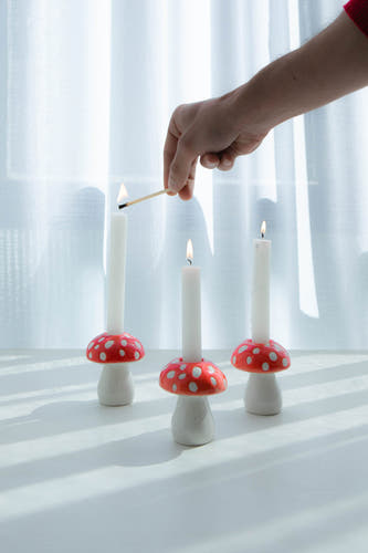 Cadeau rouge de DOIY, avec des chandeliers en forme d'ches et des bougies blanches, où une bougie est allumée.