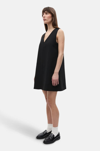 Robe noire sans manches d'ENVII, avec un col V et associée à des chaussettes blanches et des loafers noirs.