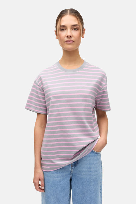 T-shirt multicolore d'ENVII, avec des rayures horizontales roses et grises, combiné avec un jean ample.