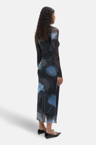 Multikleurige kleedje met lange mouwen van ENVII, met blauwe bloemenprint en gedragen met zwarte, spitse pumps.
