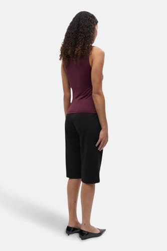 Bordeaux top sans manches d'ENVII, avec des cheveux bouclés et un pantalon noir.
