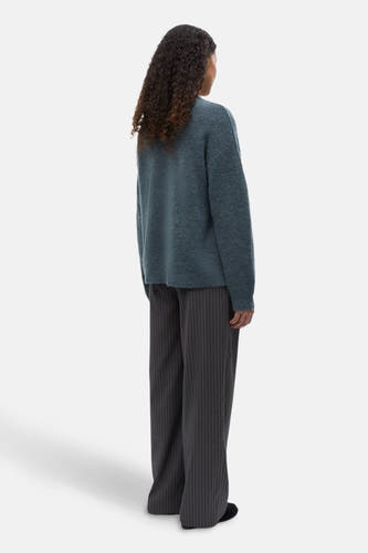 T-shirt bleu avec col rond d'ENVII, à longues manches et porté avec un pantalon rayé.