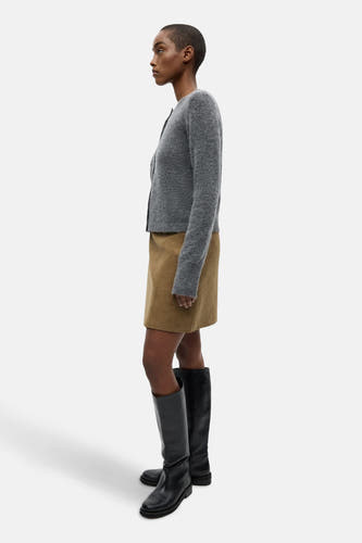Veste grise d'ENVII portée avec une jupe marron et des bottes noires jusqu'aux genoux, en vue de dos.