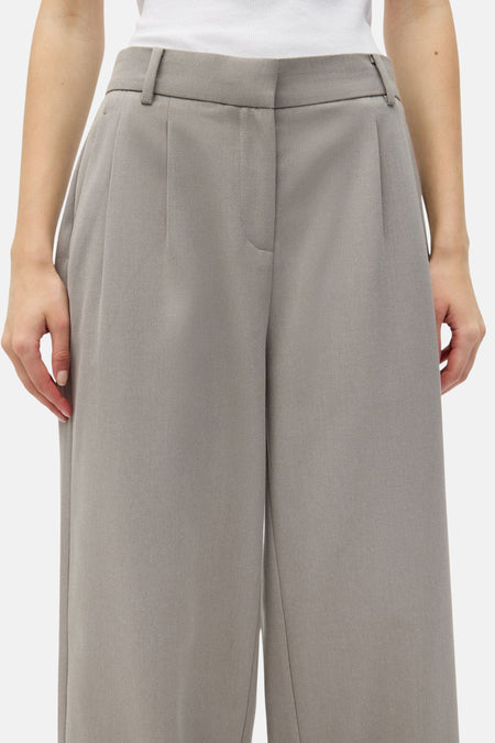 Beige broek van ENVII, met plooien en wijde pijpen, gezien van voren.
