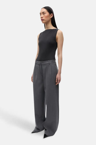 Pantalon gris d'ENVII, avec des jambes larges et des plis à l'avant, associé à une chemise noire.