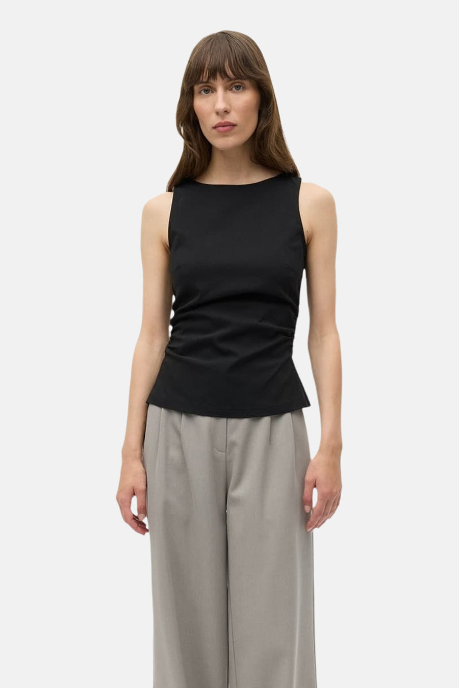 Haut noire d'ENVII, sans manches avec une coupe ajustée et portée avec un pantalon gris ample.