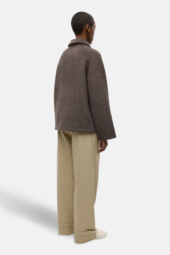 Manteau court brun d'ENVII, avec des manches longues et un col, porté avec des pantalons beige.
