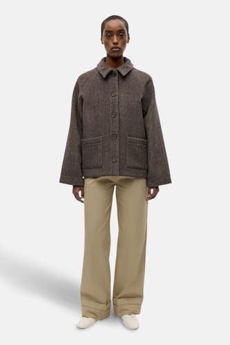 Veste brune d'ENVII, avec des manches longues, une fermeture à boutons et des poches broiquées, associée à un pantalon kaki et des chaussures blanches.
