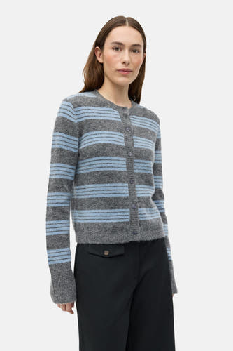 Gilet gris d'ENVII, avec un motif rayé et associé à une culotte noire et des bottes en cuir noires.