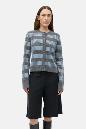 Gilet gris d'ENVII avec des rayures bleues, porté avec des culottes noires et des bottes noires.