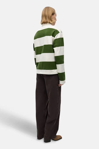 Polo vert de manues longs ENVII, avec des hores horizontales et porté avec un pantalon marron.