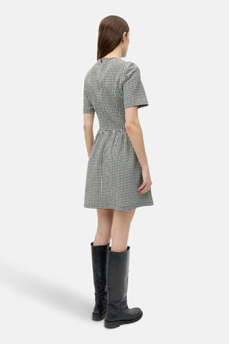 Robe blanche à manches courtes d'ENVII, avec un motif à carreaux noir et blanc et des bottes noires.