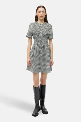 Robe blanche à manches courtes d'ENVII, avec un motif rayé noir et blanc et portée avec des bottes noires.