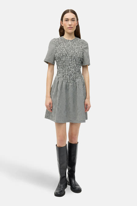 Robe blanche à manches courtes d'ENVII, avec un motif rayé noir et blanc et portée avec des bottes noires.