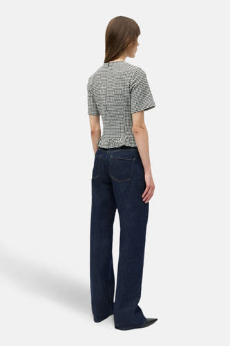 Blouse blanche à manches courtes de ENVII avec des smocks en bas, associée à un jean bleu marine.