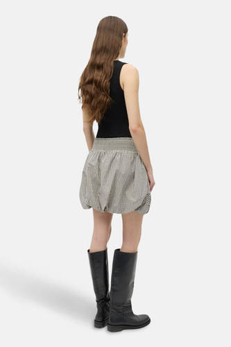 Short beige skirt from ENVII, with a checked pattern and combined with black boots and a top.