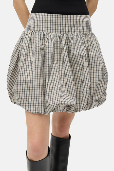 Robe courte beige d'ENVII, avec un motif à carreaux et portée avec des bottes noires.