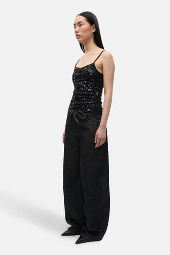Jean délavé noir d'ENVII, avec ceinture à cordon et associé à un haut en paillettes noires.