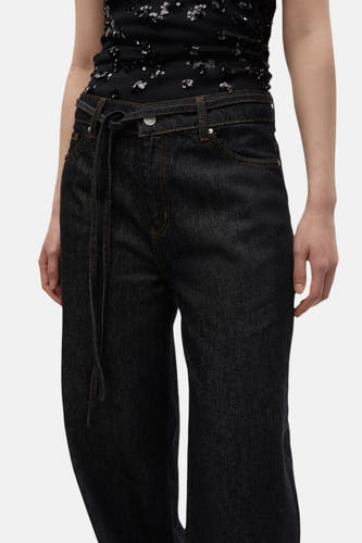 Jean délavé noir d'ENVII, avec une ceinture à la taille et des points orange.