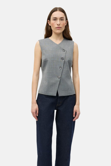 Blazer grise d'ENVII, avec fermeture boutonnée asymétrique et fines rayures verticales. Portée avec un jean foncé.