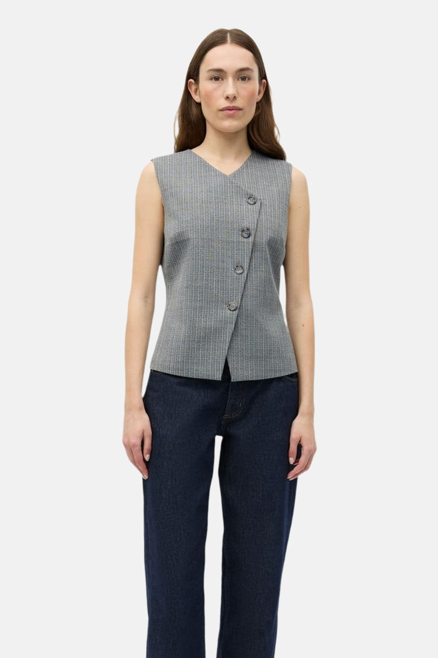Blazer grise d'ENVII, avec fermeture boutonnée asymétrique et fines rayures verticales. Portée avec un jean foncé.