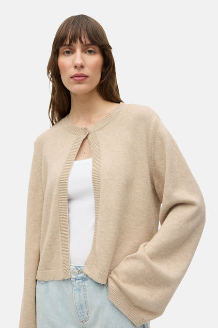 Gilet beige de ENVII, porté sur une chemise blanche et un jean clair.