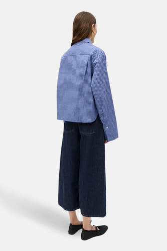 Chemise bleue à manches longues ENVII, à motif à carreaux, portée avec un jean ample bleu foncé et des chaussures noires.
