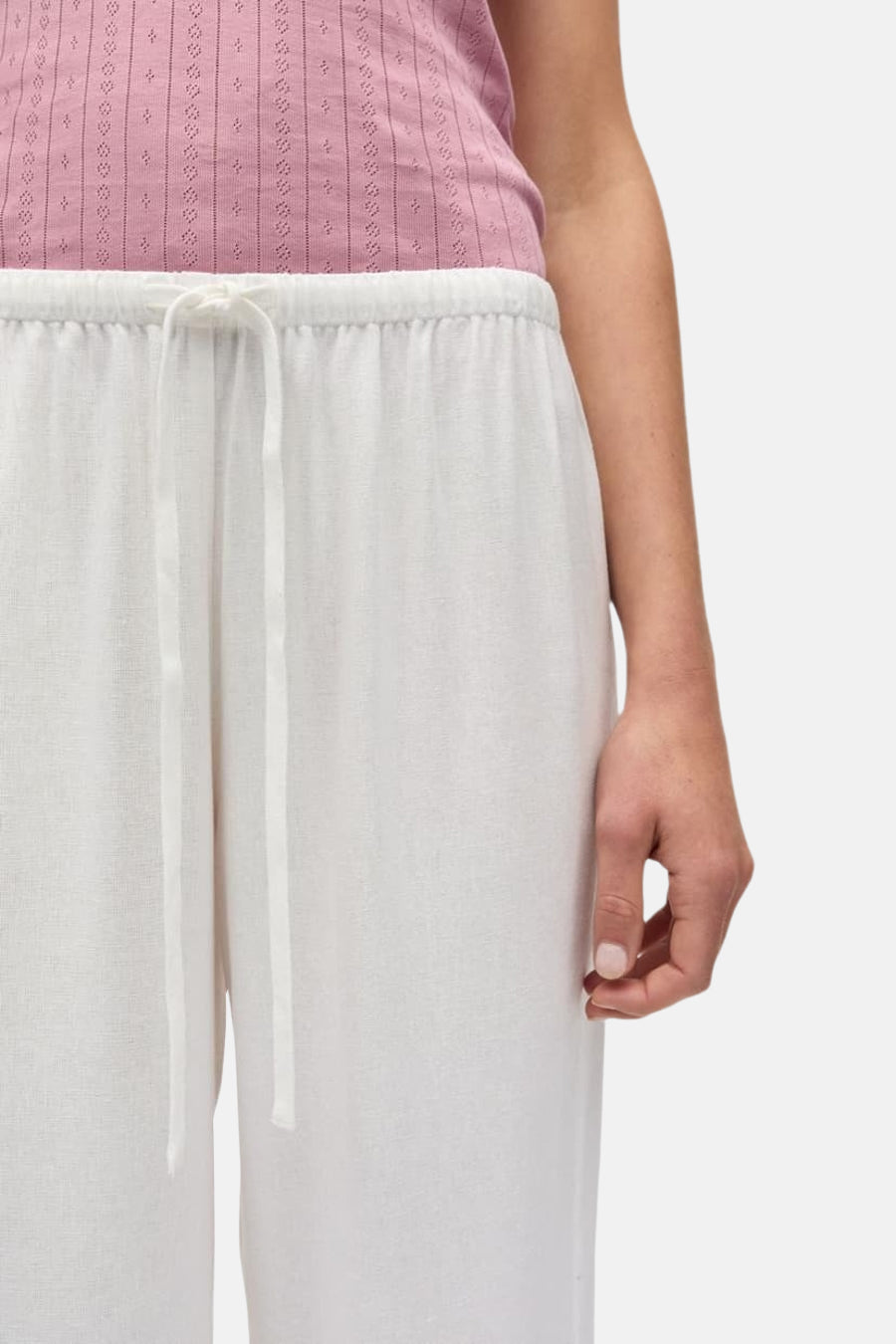 Pantalon blanc d'ENVII avec cordon de serrage à la taille, texture lin léger et une partie d'un haut rose.