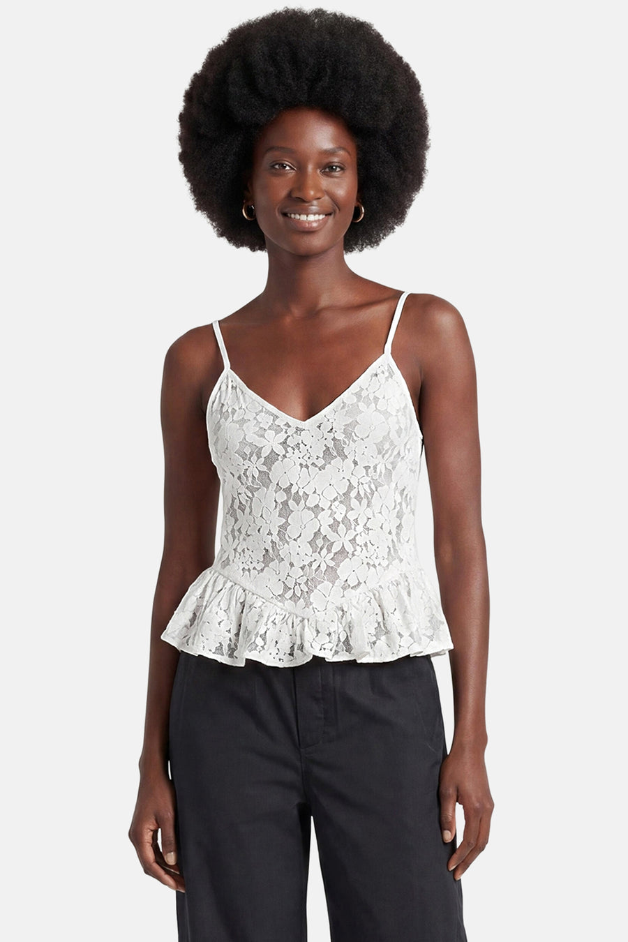 Witte mouwloze kanten blouse van ENVII met spaghettibandjes, V-hals en gerimpelde peplumzoom, gedragen met zwarte broek.