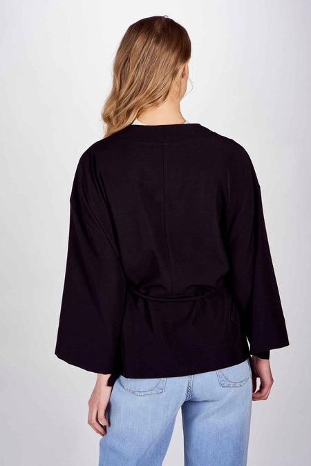 Zwarte blazer van DEUX. by Eline De Munck, met wijde mouwen en een tailleband, gezien van achteren.

