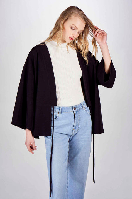 Blazer noir DEUX. par Eline De Munck, porté sur un t-shirt à manches rayées blanc et des jeans bleus.