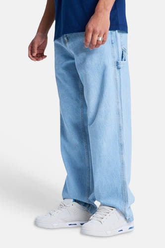 Lichtblauwe denim jeans met speciale pasvorm van DC SHOES, met wijde pijpen, gereedschapslus, witte sneakers en zilveren ring.